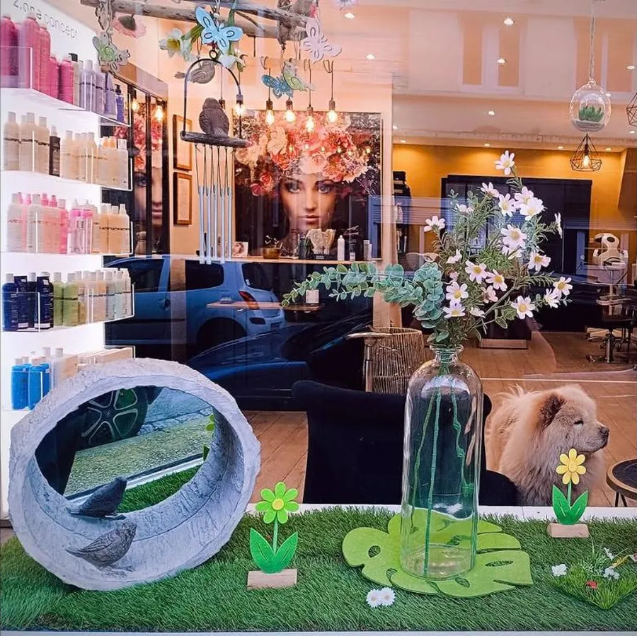 L'intérieur du salon vu de la vitrine, mur de produits et postes de coiffage — Cocoon by Emilie à Calais